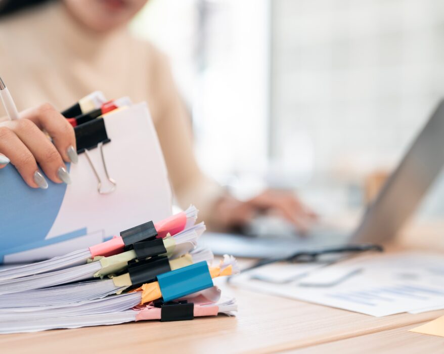 Businesswoman hands working in Stacks of paper files for searching and checking unfinished document