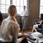 Standing female manager talking to team at casual meeting