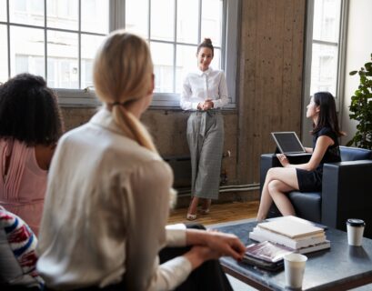 Standing female manager talking to team at casual meeting